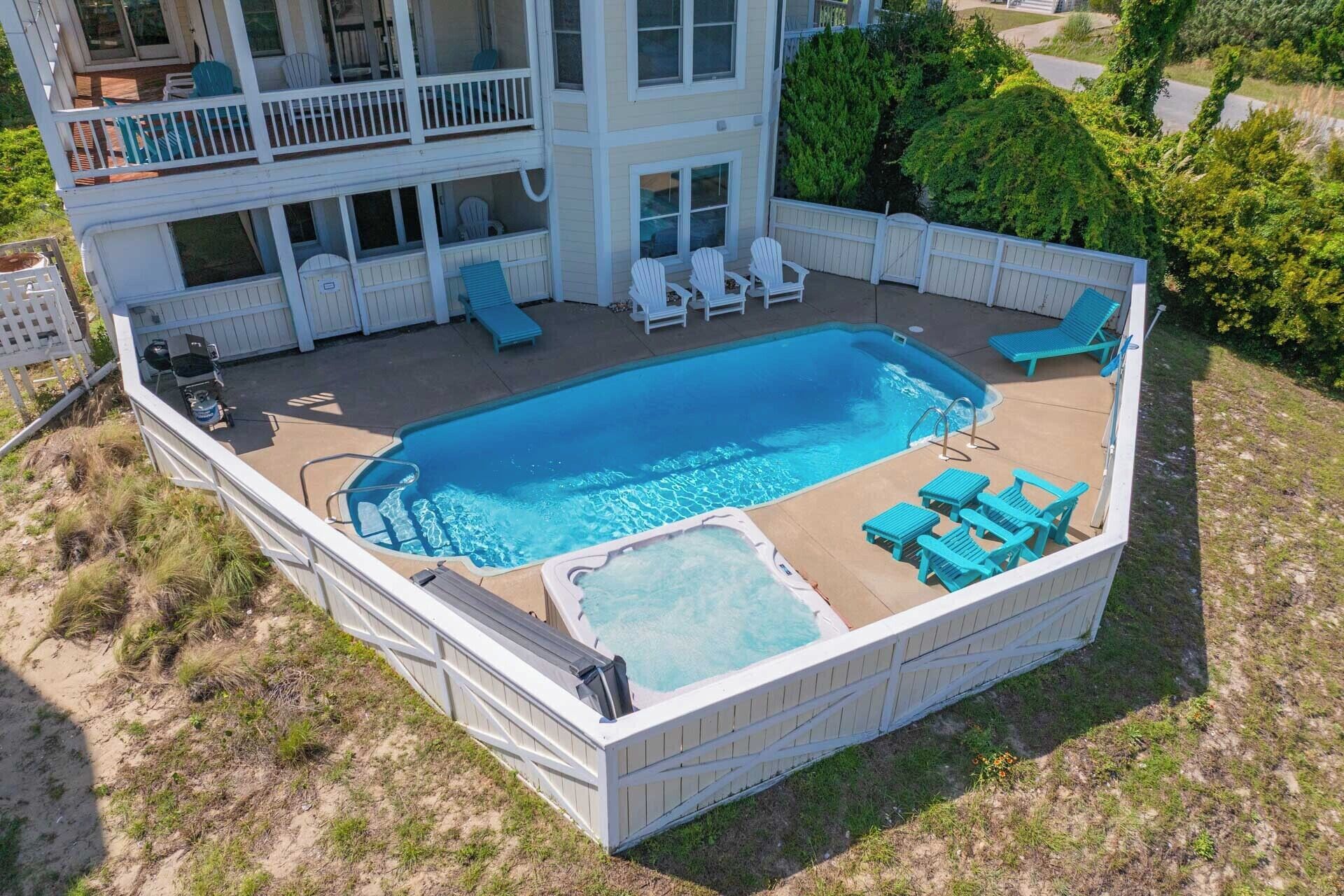 A two-story building with a rooftop pool area featuring lounge chairs and a hot tub.