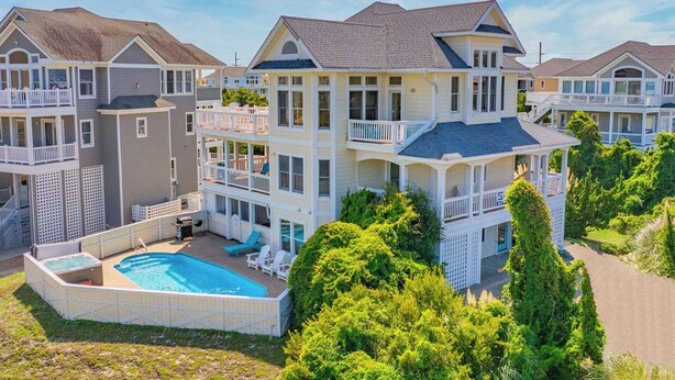A multi-story residential building with a swimming pool, balconies, and a well-maintained lawn. - Semi-Oceanfront Dog Friendly w/ Pool, Hot Tub, Home Theater, and Game Room (Avon)