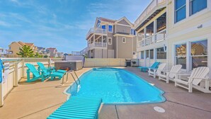 A swimming pool with blue chairs and a hot tub area. - Semi-Oceanfront Dog Friendly w/ Pool, Hot Tub, Home Theater, and Game Room (Avon)