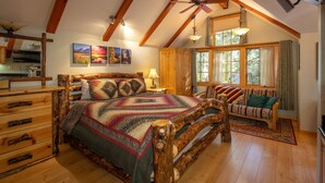 Un dormitorio acogedor con una cama y un banco de madera, y un ventanal con cortinas.