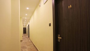 A hotel corridor with a marble floor, a wooden door with the number 14, and a light switch on the wall. - OYO 5048 Church View (Kolkata)