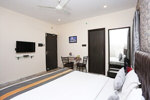 A hotel room with a bed, a TV mounted on the wall, a table with chairs, and a mirror. - OYO 5048 Church View (Kolkata)