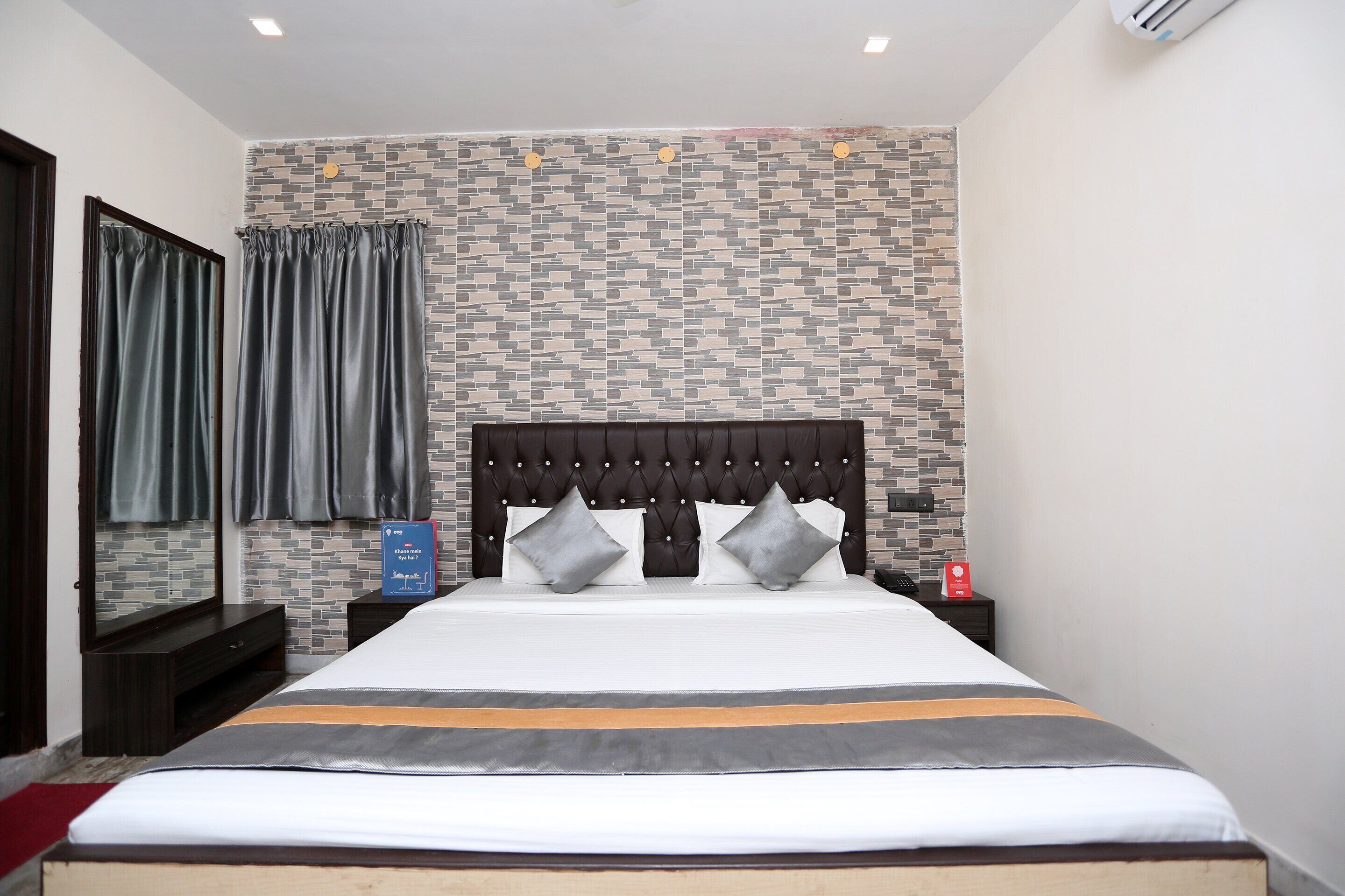 A neatly made bed with a striped bedspread, a tufted headboard, and two bedside tables with lamps.
