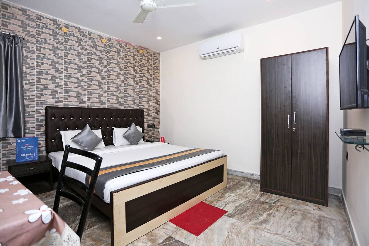 A bedroom with a bed, a chair, a wardrobe, and a TV.