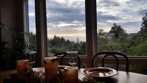 A dining table with a view of a sunset through large windows, surrounded by chairs and various tableware. - Need to get away? This is your home away from - everything!
SEAGLASS Irish Beach (Manchester)