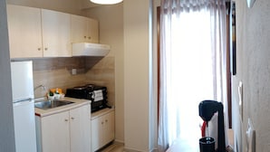 A compact kitchen with light wooden cabinets, a built-in oven, and a small countertop. - Prosforio Rooms (Aristotelis)