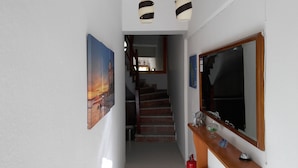 A hallway with a staircase leading to a room, a large mirror, and a painting on the wall. - Prosforio Rooms (Aristotelis)
