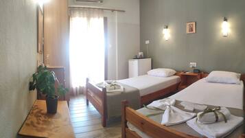 A hotel room with two beds, a desk, a chair, a potted plant, a wardrobe, and a window with curtains.