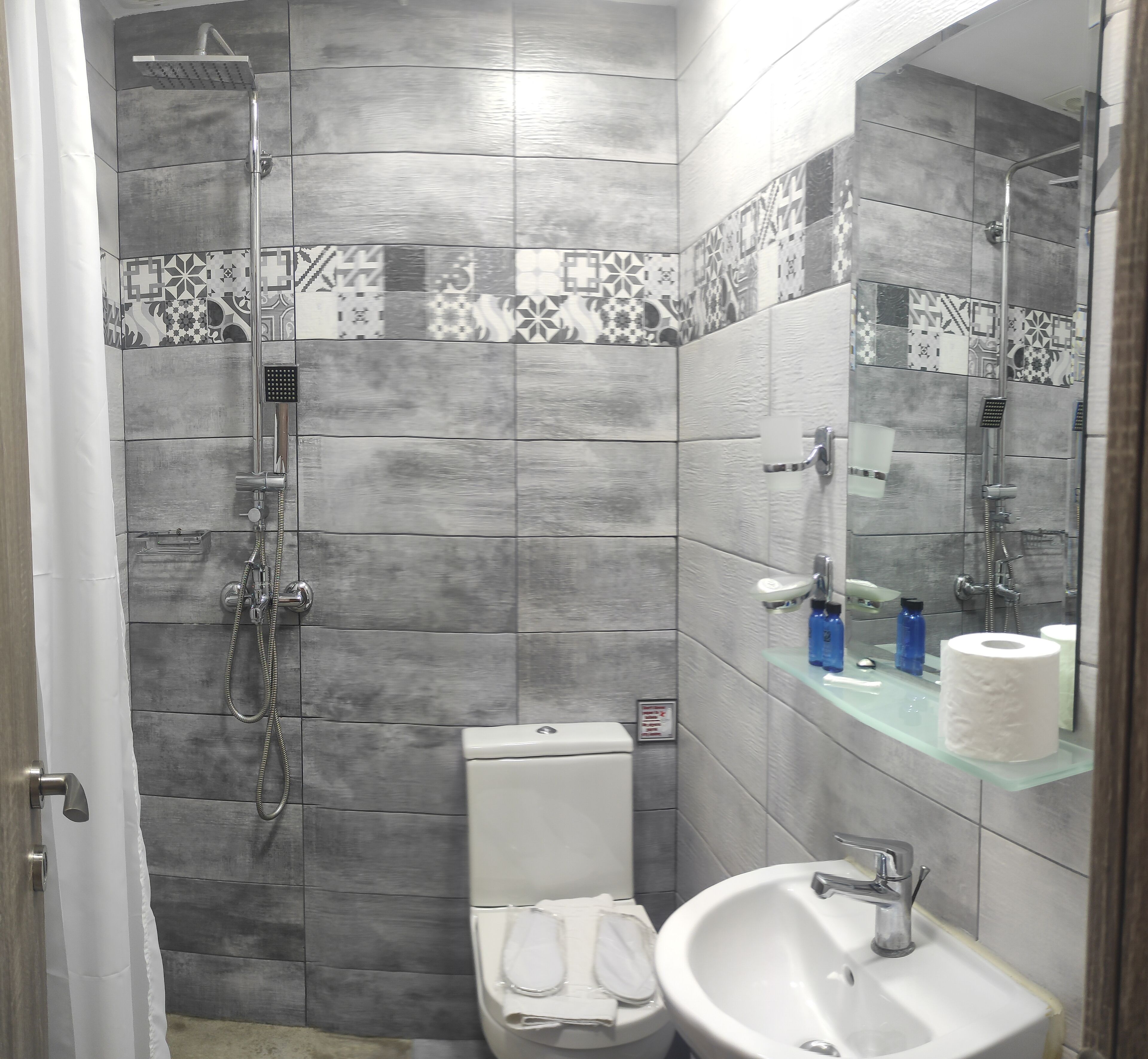 Ein Badezimmer mit Dusche, Toilette, Waschbecken und Spiegel.