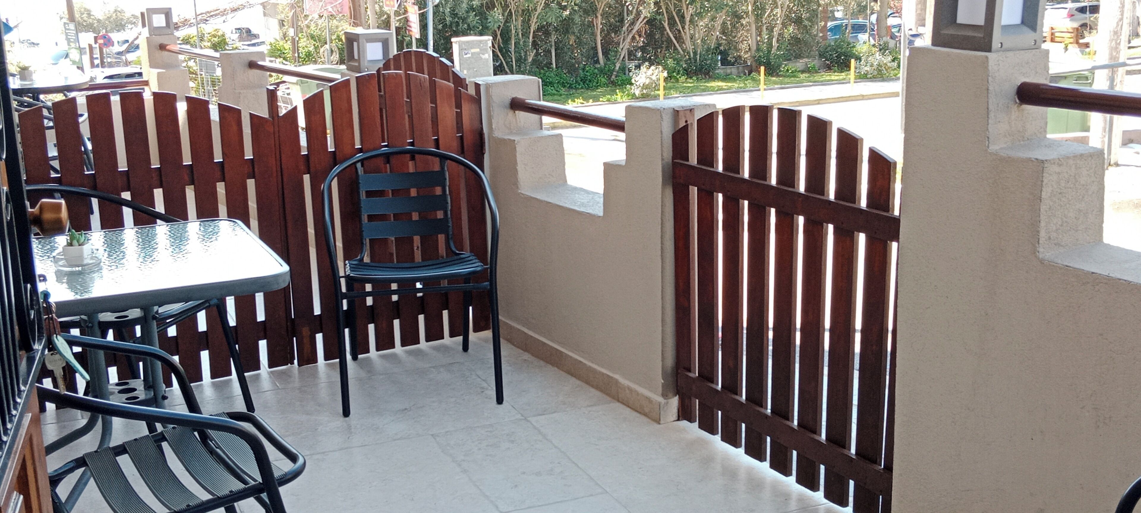A balcony with a table and chairs, a potted plant, and a wooden fence.