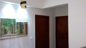 A hallway with two wooden doors and a wall-mounted picture of a forest path. - Prosforio Rooms (Aristotelis)