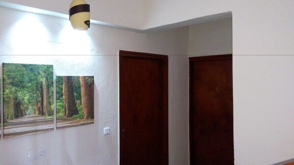 A hallway with two wooden doors and a wall-mounted picture of a forest path.
