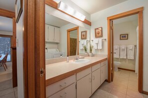 Une salle de bain avec un lavabo, un miroir et des meubles en bois.