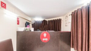 A reception area with a brown counter, a sign with a heart symbol, and a "NO SMOKING" sign on the wall. - OYO 9543 Rajarhat (Barasat)