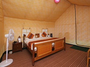 A room with a wooden bed, a nightstand, a fan, and patterned wallpaper. - OYO 9485 Swiss Camps (Kullu)