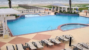 Un espace piscine avec des chaises longues et vue sur la plage.