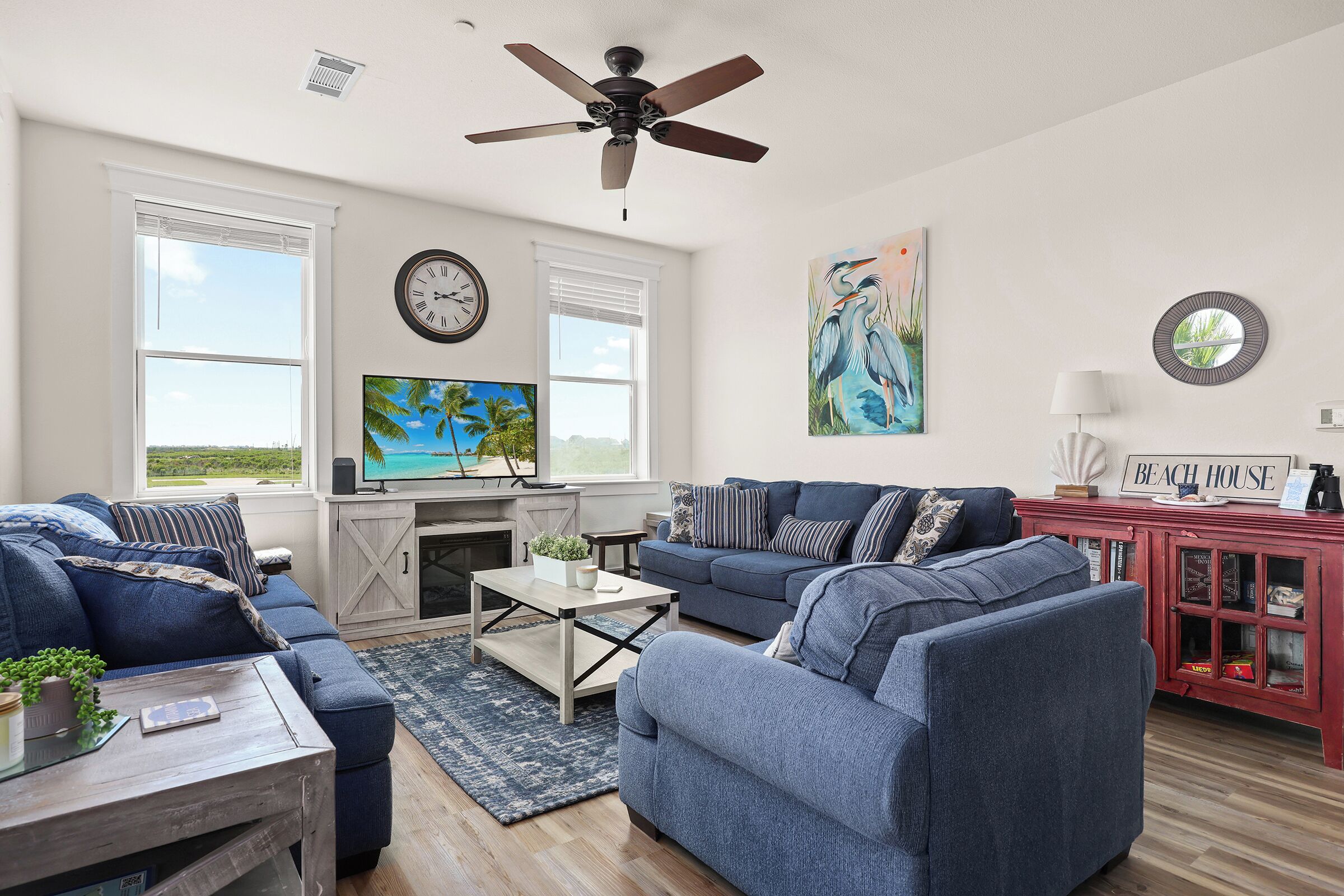 A living room with a sofa, coffee table, and TV, a red cabinet, and a ceiling fan.