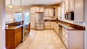 A modern kitchen with wooden cabinets, stainless steel appliances, and a granite countertop. - Oceanview Home with Hot Tub, Game Room, Wet Bar, Grill. Feel That Summer Breeze! (Salvo)