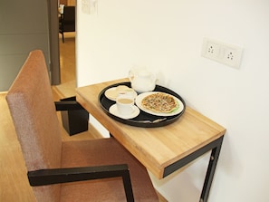 A small dining table with a tray containing a teapot, cups, and a plate of food.