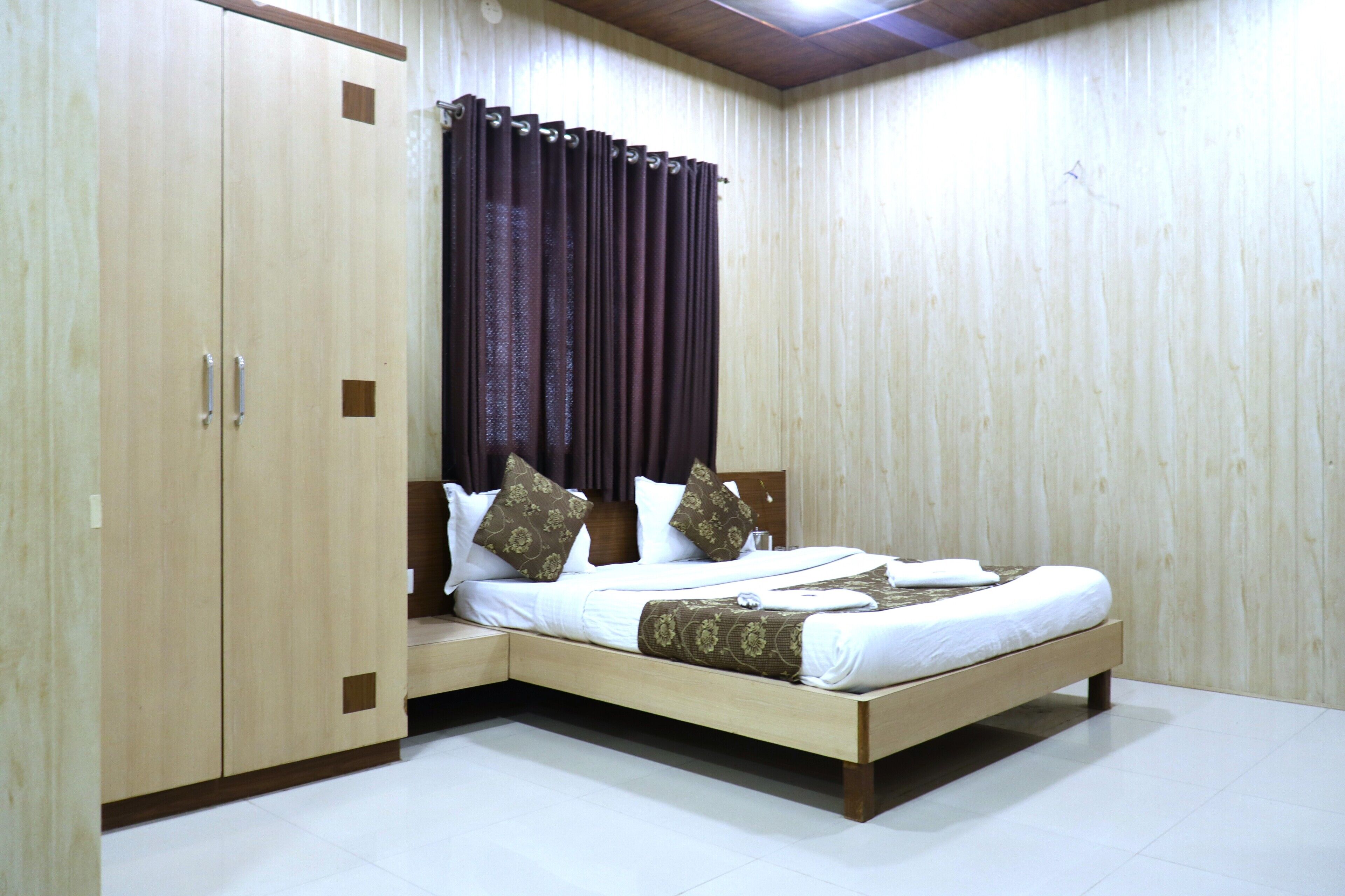 A bedroom with a bed, wooden wardrobe, and curtains.