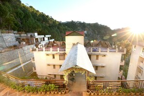A multi-story building with a central atrium, surrounded by balconies and potted plants. - OYO 10976 Home Cheerful 2BHK Scenic Barog (Solan)