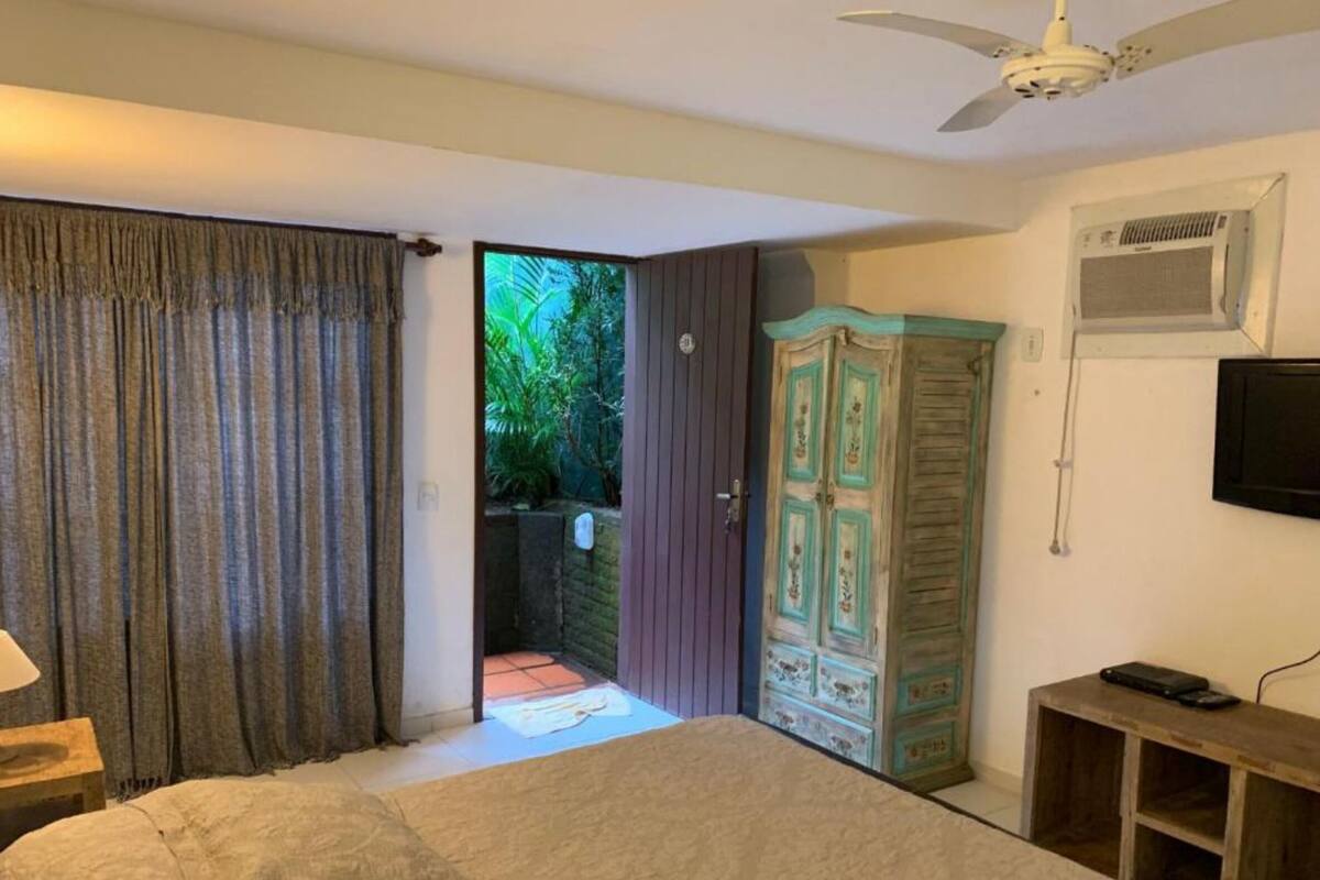 Une chambre à coucher comprenant un lit, une armoire, un téléviseur et un ventilateur de plafond.