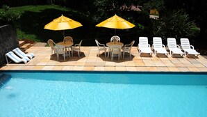 A swimming pool with lounge chairs and umbrellas. - Hotel Daniela (Itatiaia)