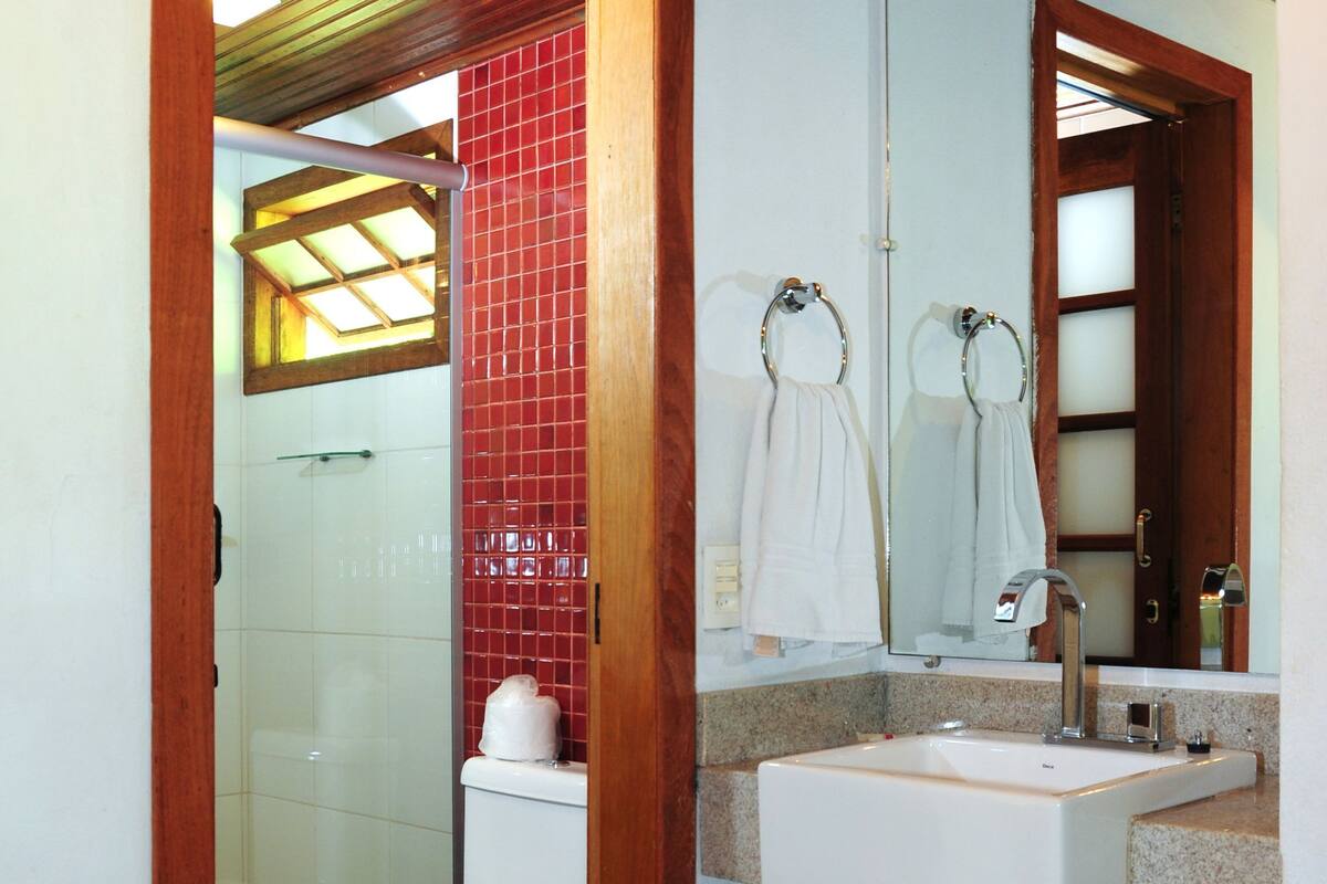 A bathroom with a toilet, sink, mirror, and shower.