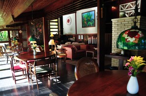 A cozy interior with a dining area, a sofa, and a fireplace. - Hotel Daniela (Itatiaia)