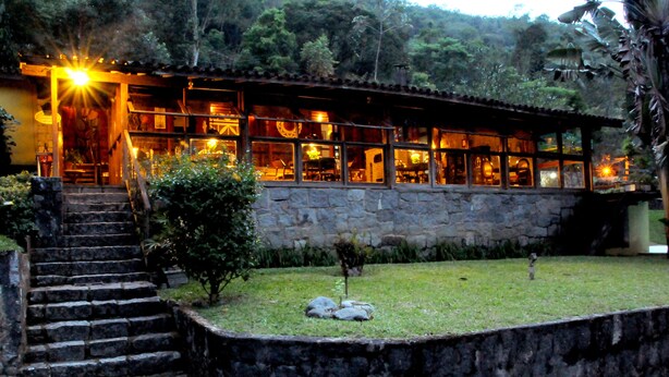 A stone building with a stone staircase leading to a wooden door. - Hotel Daniela (Itatiaia)