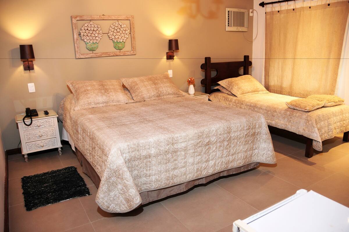 A bedroom with two beds, a nightstand, a lamp, and a decorative wall piece.