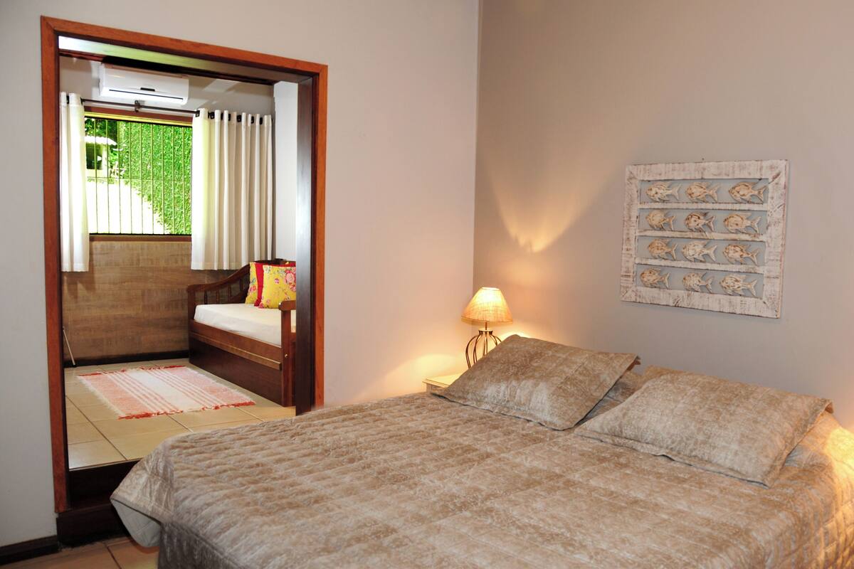 A bedroom with a bed, bedside lamps, a wall-mounted artwork, and a window with curtains.