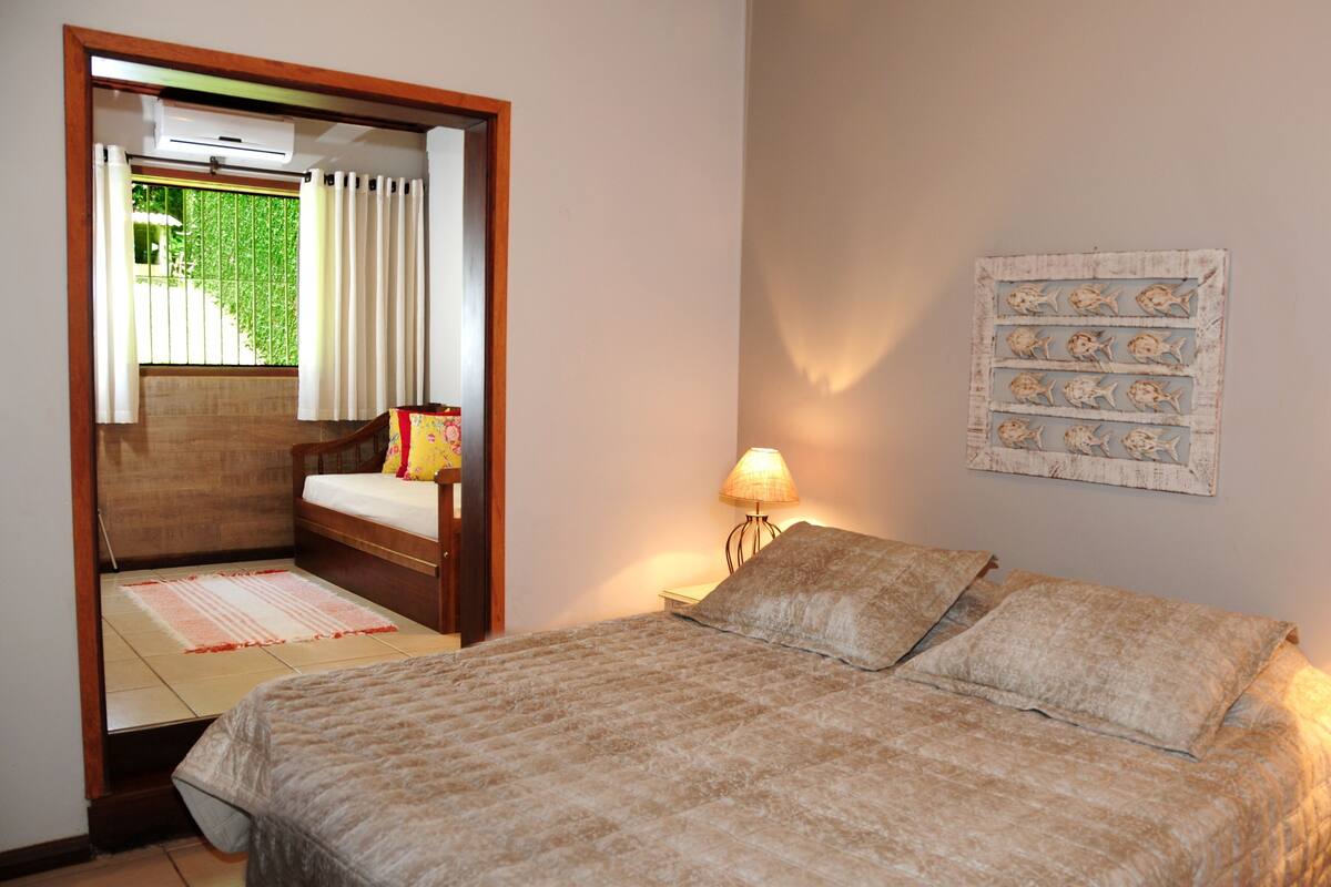 A bedroom with a bed, bedside lamps, a wall-mounted artwork, and a window with curtains.