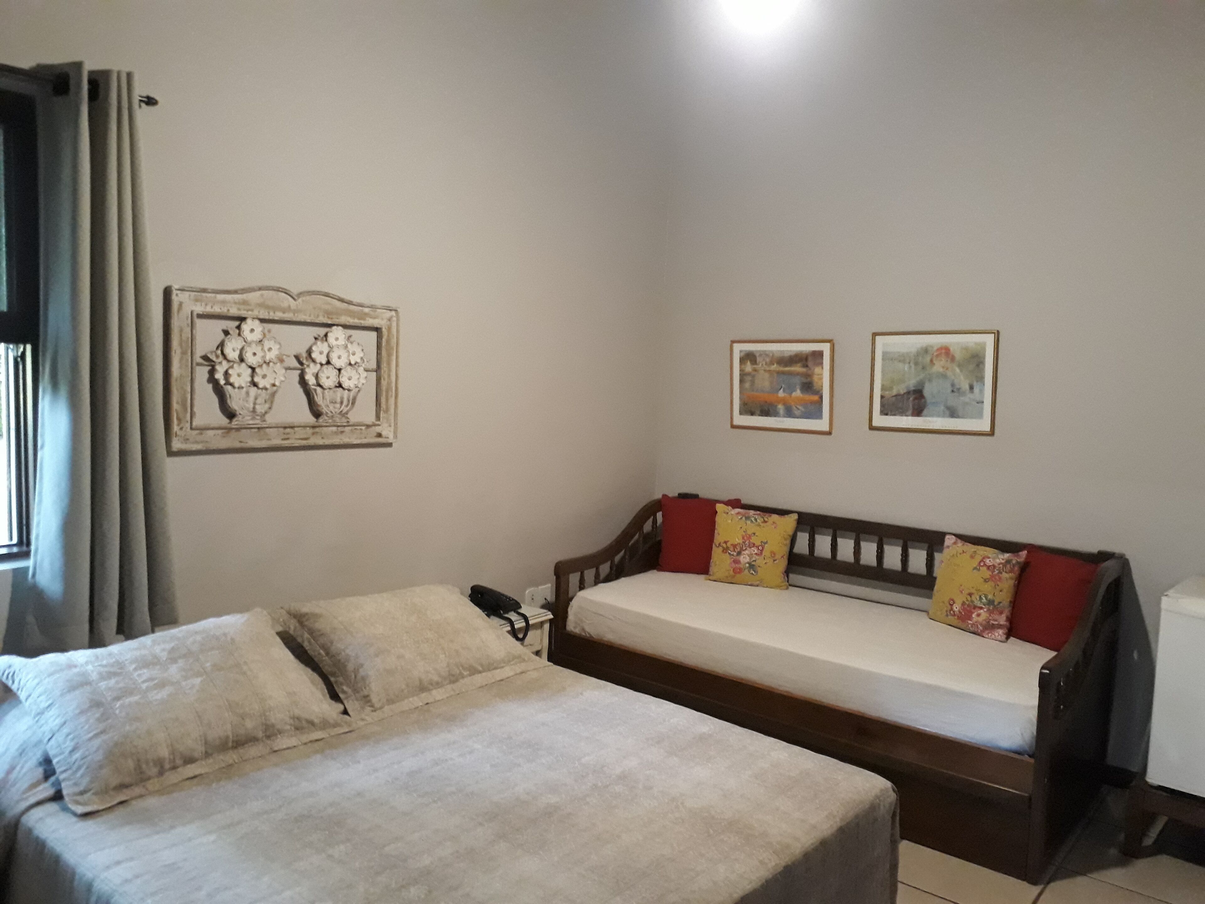 Una habitación con una cama, un sofá y dos cuadros en la pared.