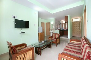 A living room with a TV, wooden furniture, a glass coffee table, and a sofa. - OYO 10409 Home Cozy 4BHK New Shimla (Shimla)