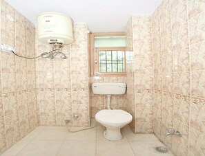 A small bathroom with a toilet, a window, and a water heater. - OYO 10409 Home Cozy 4BHK New Shimla (Shimla)