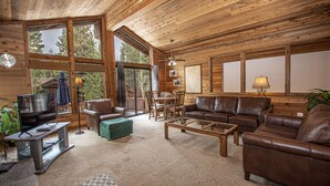 A cozy cabin interior with a wooden ceiling, leather sofas, a TV, and a dining area. - Vance by Hauserman Rentals (Tahoe City)