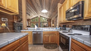 A kitchen with wooden cabinets, a dishwasher, a stove, and a microwave. - Vance by Hauserman Rentals (Tahoe City)