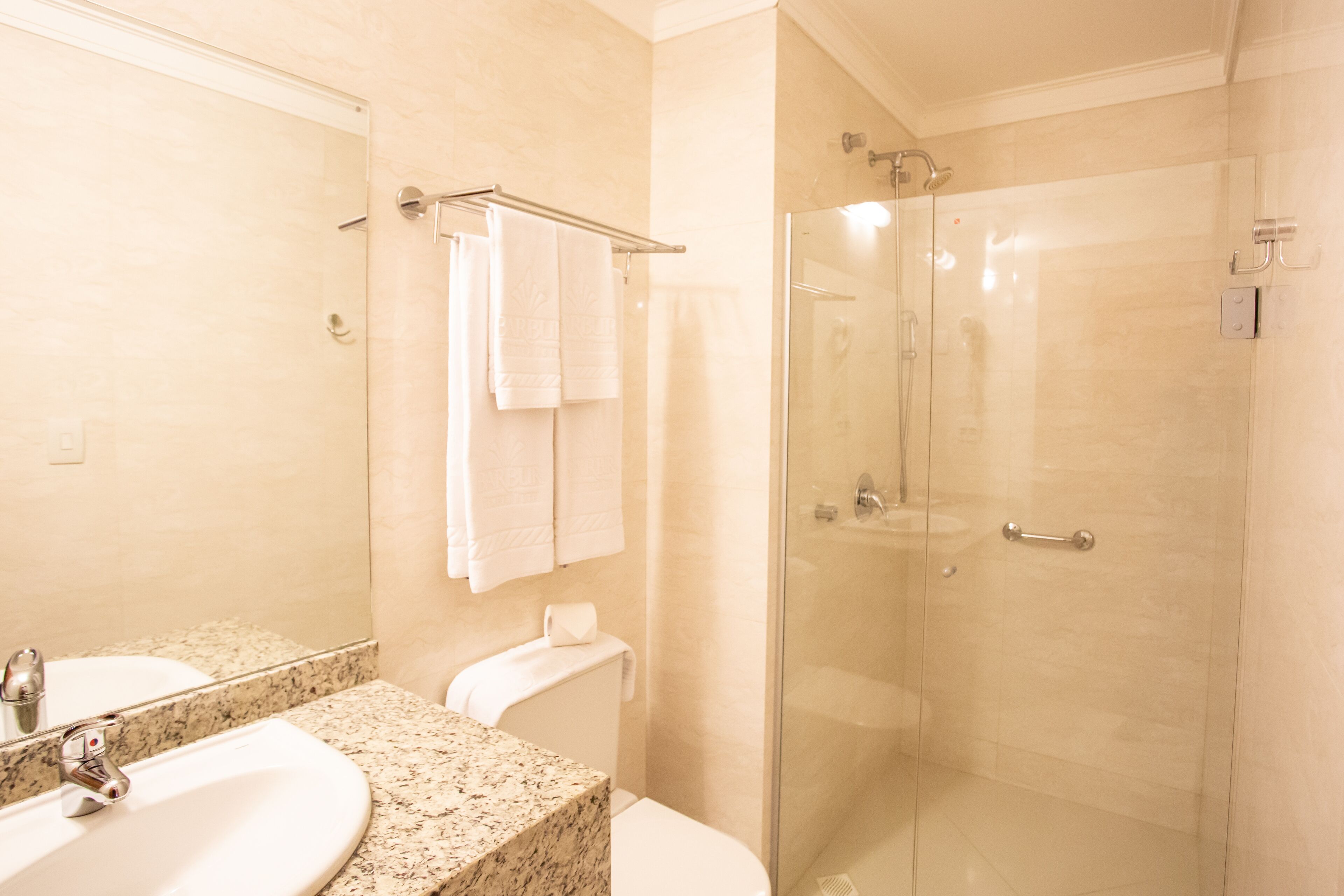 A bathroom with a sink, mirror, toilet, and glass-enclosed shower.