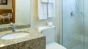 A modern bathroom with a granite countertop sink, a toilet, and a glass-enclosed shower.
