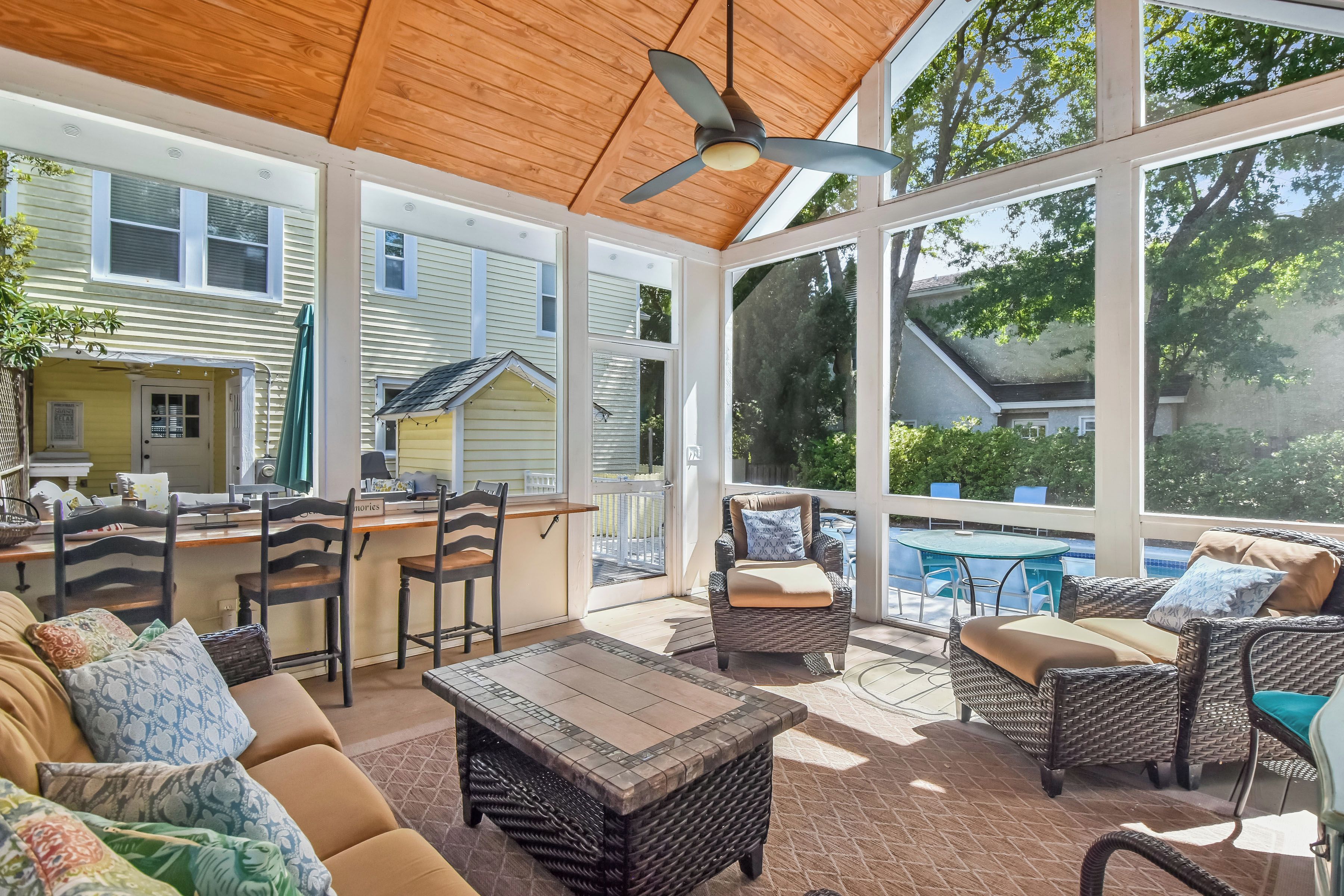 A covered patio area with wicker furniture, a dining table, and chairs.