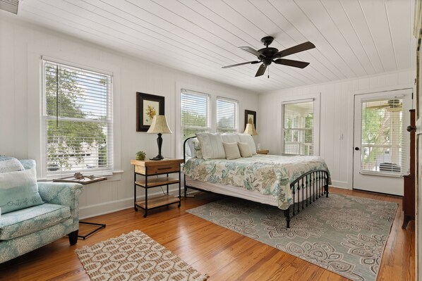 A bedroom with a bed, a nightstand, a lamp, a chair, and a ceiling fan. - Seventh Heaven Beach House on East Beach with Private Pool! (St Simons Island)