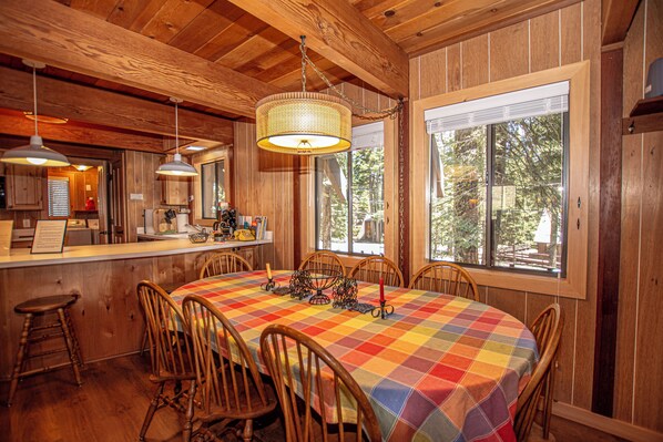 A dining area with a checkered tablecloth, wooden chairs, and a hanging light fixture.