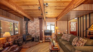 Un salon chaleureux avec une cheminée, un plafond en bois et un canapé confortable.