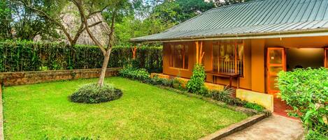 A house with a well-maintained lawn, a small tree, and a metal roof.
