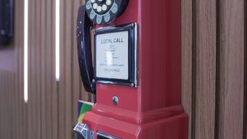 Un teléfono público rojo con teclado numérico y distintivo de llamadas locales.