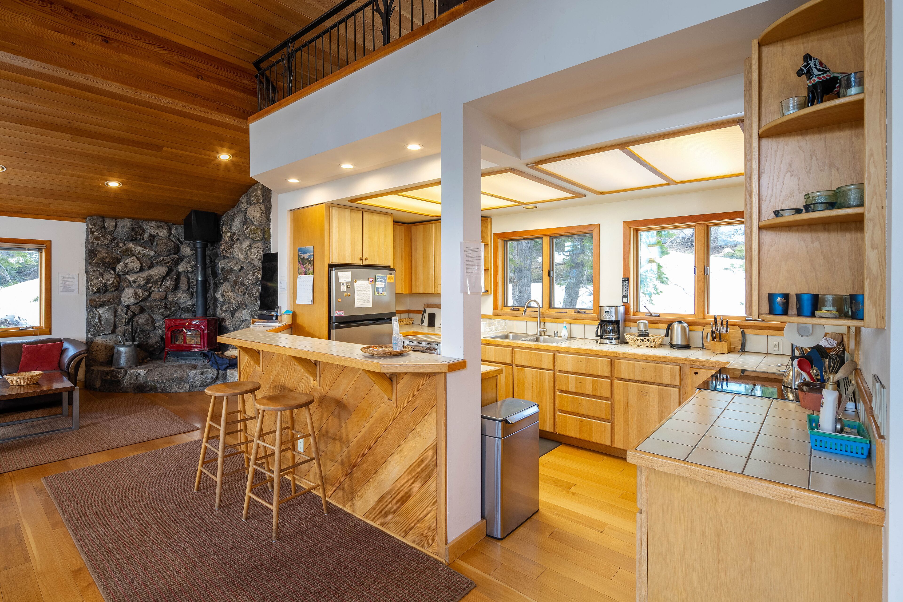Une cuisine moderne avec un îlot central, des armoires en bois et un mur en pierre.