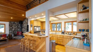 A modern kitchen with a central island, wooden cabinets, and a stone wall.