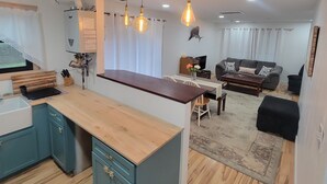 Eine moderne Küche mit Holzarbeitsplatte, ein Essbereich mit Tisch und Stühlen, eine Couch und eine Wanddekoration.