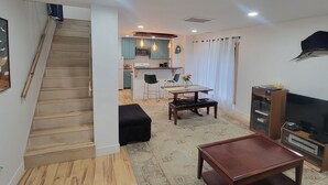 Eine moderne Wohnung mit einer Treppe, die zu einer Küche, einem Essbereich mit Tisch und Stühlen sowie einem Wohnzimmer mit Fernseher und kleinem Tisch führt.